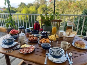 Ett frukostbord med olika sorters mat, bestick och en krukväxt.