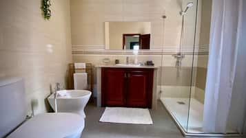Een badkamer met toilet, bidet en een douchecabine.