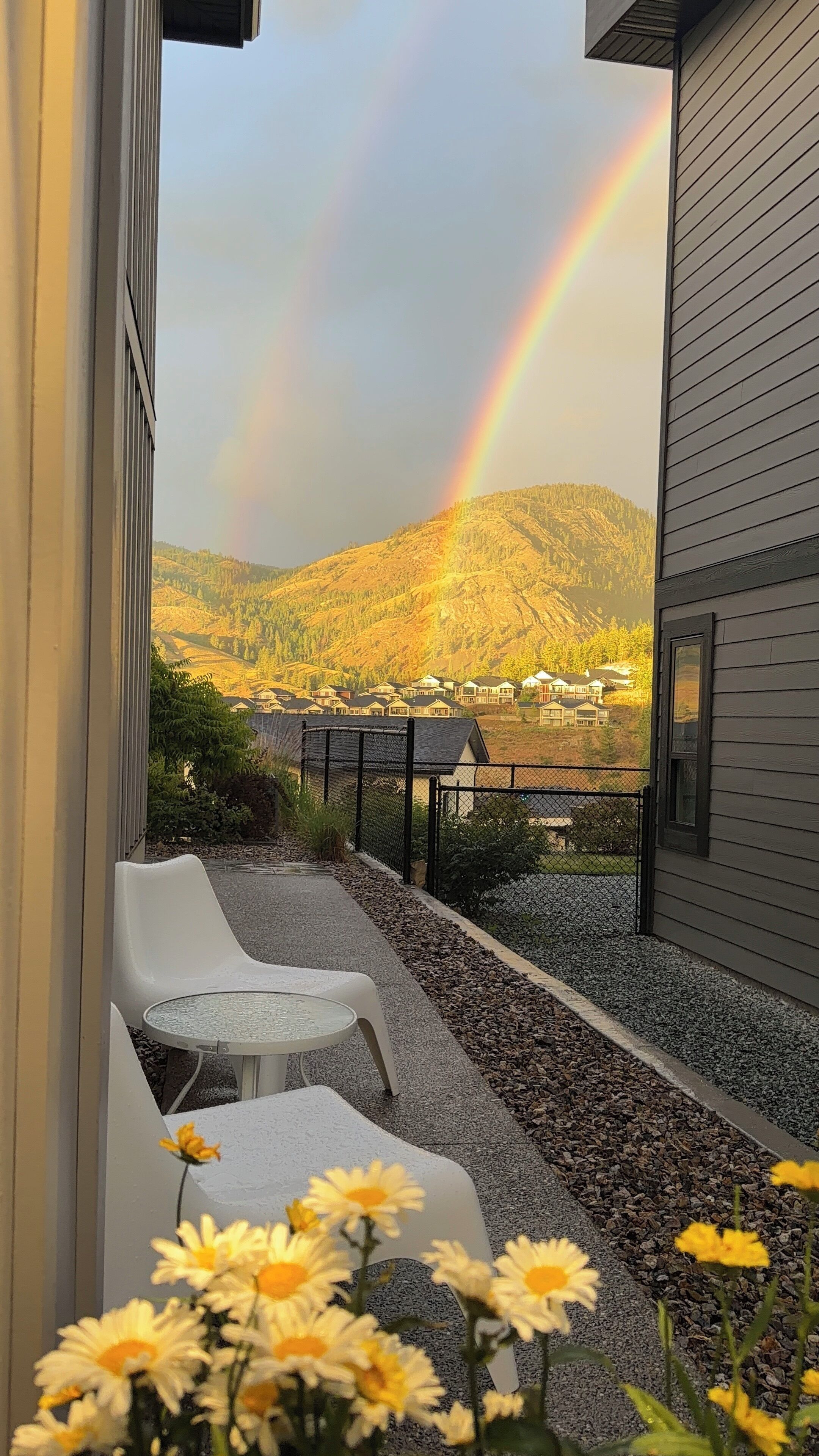En balkon med udsigt til et bjerglandskab og en regnbue.