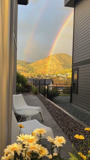 Ein Balkon mit Blick auf ein Gebirge und einen Regenbogen.