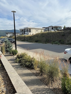 A parking area with a row of cars, a street lamp, and a building with a flat roof in the background. - New* Black Mountain Cozy Modern 2bedroom Private Suite (Kelowna)