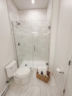 Et moderne badeværelse med bruseniche, toilet og badekar.