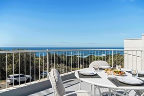 An outdoor dining area with a table set for two, overlooking a coastal view. - Point Arkwright Escape - Rooftop, Pool & Views (Coolum Region)