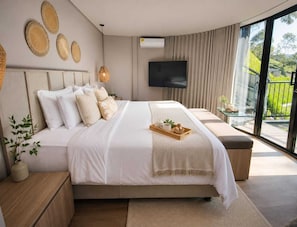 A modern bedroom with a large bed, a flat-screen TV, and a balcony with a view. - Hotel Velto Serene (El Peñol)