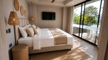 Un dormitorio moderno con una cama grande, ventilador de techo, televisión de pantalla plana y vistas a zonas verdes a través de amplios ventanales.