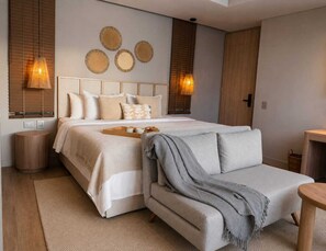 A bedroom with a bed, bedside lamps, a bedside table, a sofa, and a wall-mounted artwork. - Hotel Velto Serene (El Peñol)