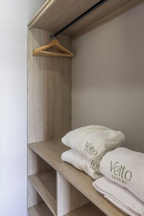 Un armario de madera con una barra para colgar y dos toallas dobladas con la marca 'Velto'.