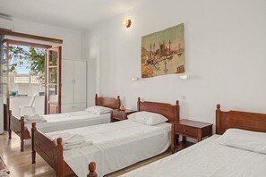 A hotel room with two single beds, a wooden headboard, a small bedside table, a nightstand, and a painting on the wall. - Room 'Orama 25' with Sea View, Wi-Fi and Air Conditioning (Εύβοια)