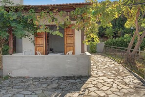 A stone-paved courtyard with a rustic building featuring wooden doors and a small seating area. - Room 'Orama 25' with Sea View, Wi-Fi and Air Conditioning (Εύβοια)