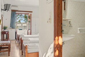 A hotel room with a bed, a desk, a chair, a small table, a plant, and a view of the outside. - Room 'Orama 25' with Sea View, Wi-Fi and Air Conditioning (Εύβοια)