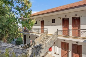 A building with multiple doors, a stone staircase, and a balcony with a metal railing. - Room 'Orama 25' with Sea View, Wi-Fi and Air Conditioning (Εύβοια)