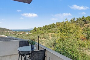 Eine Terrasse mit Tisch und Stühlen, die auf einen Hügel mit Bäumen und eine entfernte Ansicht von Häusern blickt.