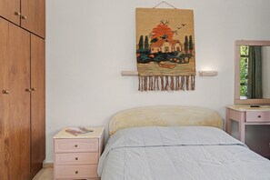 Ein Schlafzimmer mit einem Bett, einem Nachttisch, einer Kommode, einem Kleiderschrank und einem Wandteppich.