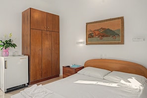 A bedroom with a bed, a wooden wardrobe, a small table with a plant, and a wall-mounted painting. - Room 'Orama 37' with Sea View, Wi-Fi and Air Conditioning (Εύβοια)
