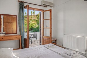 A bedroom with a bed, a wooden wardrobe, a window with curtains, and a view of a balcony with a table and chairs. - Room 'Orama 37' with Sea View, Wi-Fi and Air Conditioning (Εύβοια)