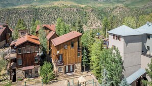 A mountain lodge with multiple wooden buildings, a stone foundation, and a view of the surrounding mountains. - Stylish Mountain Village Getaway | Fireplace, Grill & Mountain Views (Telluride)