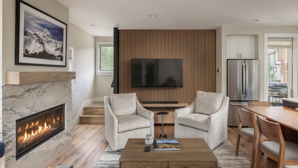 A modern living room with a fireplace, a flat-screen TV, and a dining area. - Stylish Mountain Village Getaway | Fireplace, Grill & Mountain Views (Telluride)