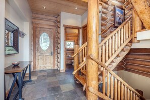A wooden staircase with a handrail, a door with a circular window, and a tiled floor. - Luxury Mountain Village Retreat | Panoramic Mountain Views | Private Hot Tub | Sleeps 9 (Telluride)