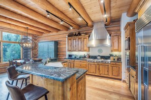 A spacious kitchen with wooden cabinets, a large island, and a stainless steel range hood. - Luxury Mountain Village Retreat | Panoramic Mountain Views | Private Hot Tub | Sleeps 9 (Telluride)