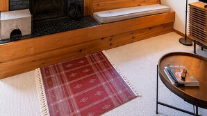 Tunnelmallinen olohuone, jossa on takka, puinen penkki ja suuri peili, joka heijastaa ulkomaailmaa.