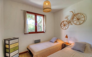 A bedroom with a bed, bedside tables, a dresser, a window with curtains, and a wall-mounted bicycle decoration. - Villa Gioia - SAN GAVINO DI CARBINI (SAN GAVINO DI CARBINI)