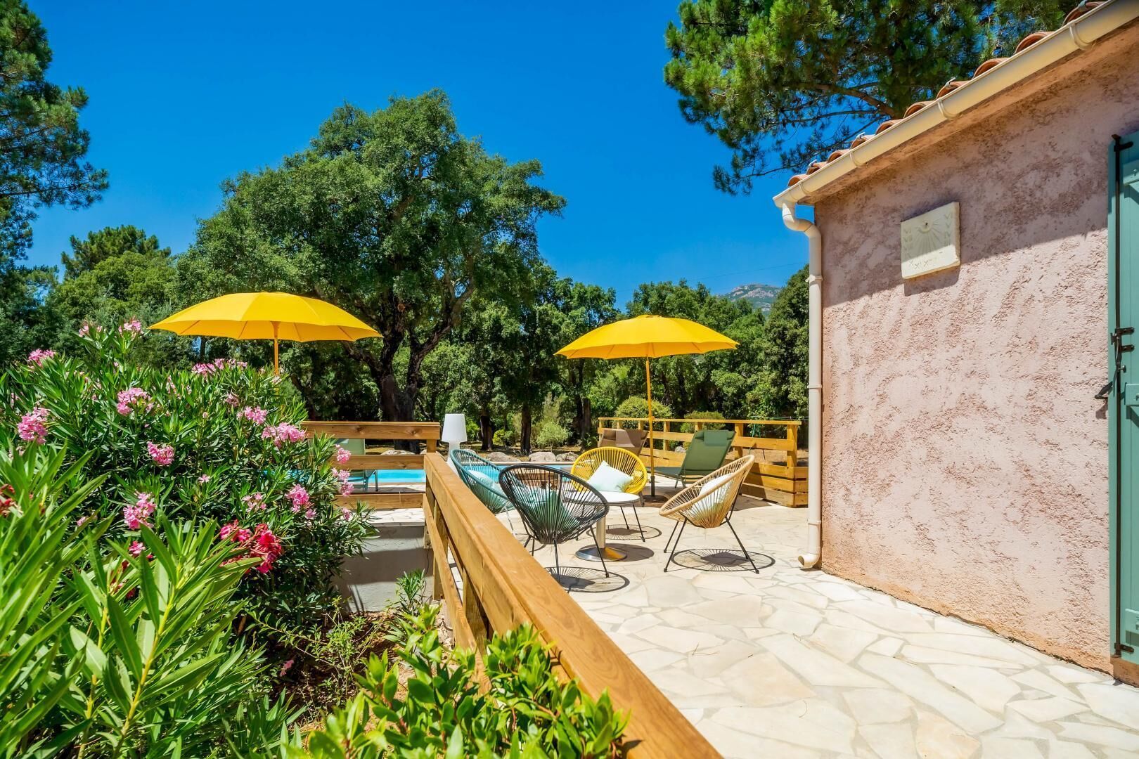 Un área de estar al aire libre con sombrillas amarillas, una piscina y un patio de piedra.