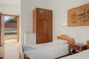 A bedroom with a bed, wooden wardrobe, a small refrigerator, and a wall-mounted painting. - Room 'Orama  19' with Sea View, Wi-Fi and Air Conditioning (Εύβοια)