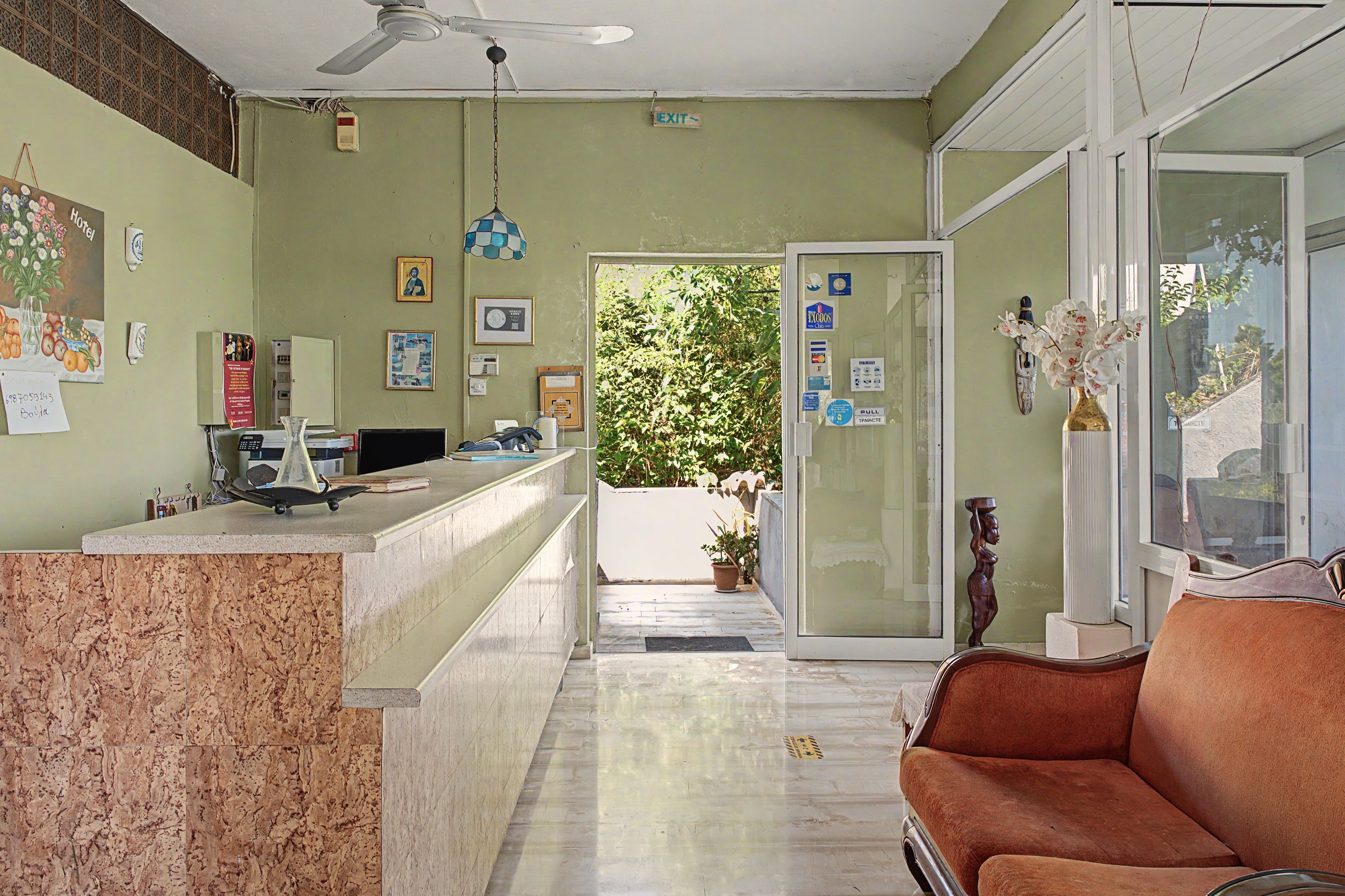 A hotel reception area with a reception desk, a computer, a telephone, and a seating area with a sofa.