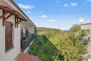 Ein Gebäude mit einem Balkon, der auf ein üppiges Grünental und einen klaren Himmel blickt.