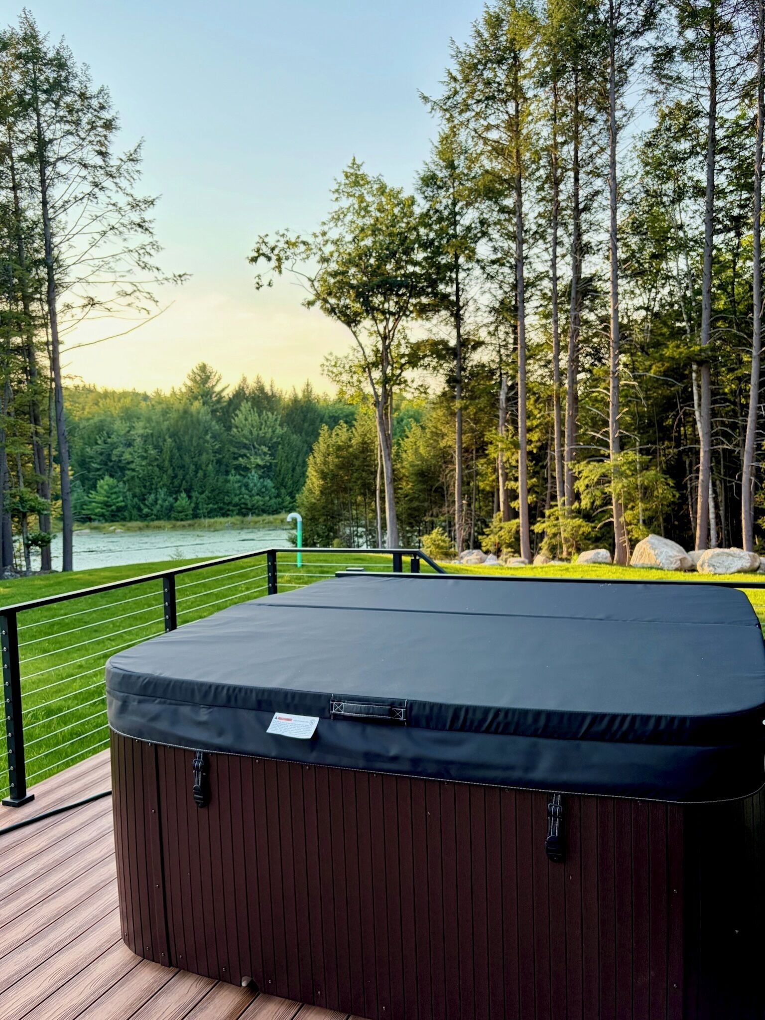 A hot tub on a deck with a view of a lake and forest.