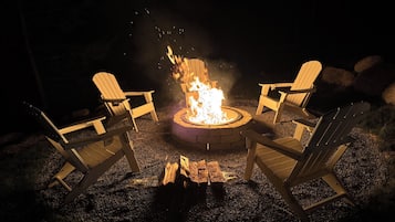 Un hogar para fuego con cuatro sillas Adirondack dispuestas alrededor.