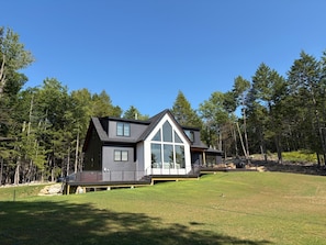 A modern two-story house with a large front window and a deck.