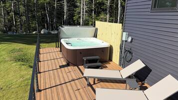 Une terrasse dotée d’un jacuzzi, de chaises longues et d’une clôture en bois.