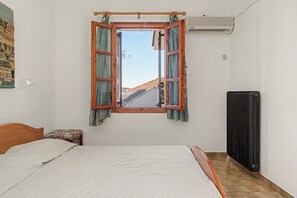 Ein Schlafzimmer mit einem Bett, einem Fenster mit Vorhängen, einer Klimaanlage und einer Heizung.