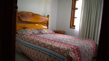 A bed with a wooden headboard, a patterned bedspread, and a bedside table.