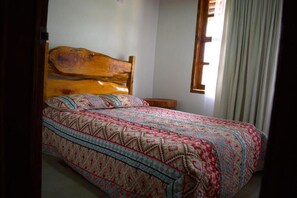A bed with a wooden headboard, a patterned bedspread, and a bedside table.