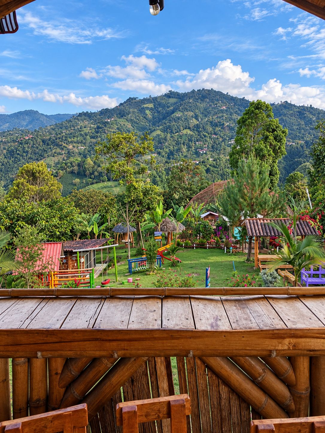 Una terraza de madera con vistas a un paisaje exuberante, colinas y edificios dispersos.
