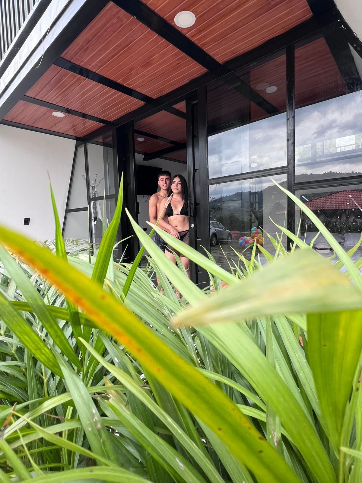 Un interior moderno con un amplio ventanal, techo de madera y vistas al exterior.
