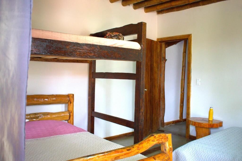 Une pièce avec des lits superposés, une porte en bois et une petite table ronde sur laquelle se trouve une bouteille.