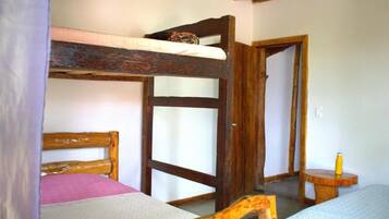 Une pièce avec des lits superposés, une porte en bois et une petite table ronde sur laquelle se trouve une bouteille.