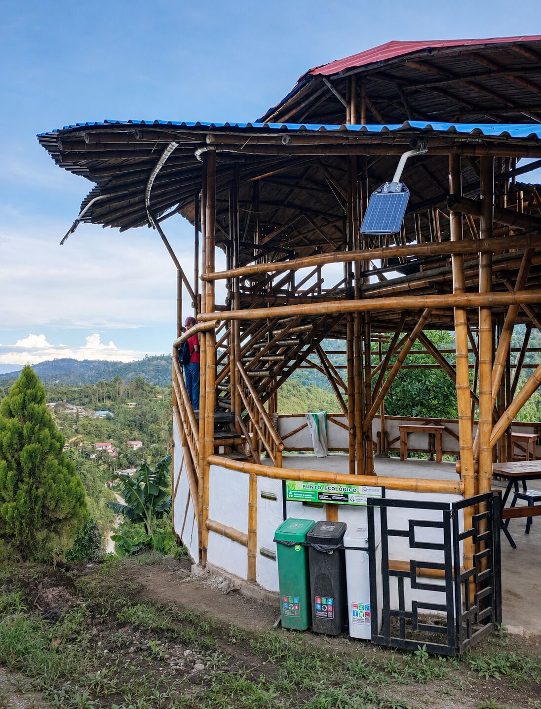 Estructura de bambú con un panel solar, asientos exteriores y contenedores de reciclaje.