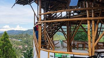 Estructura de bambú con un panel solar, asientos exteriores y contenedores de reciclaje.