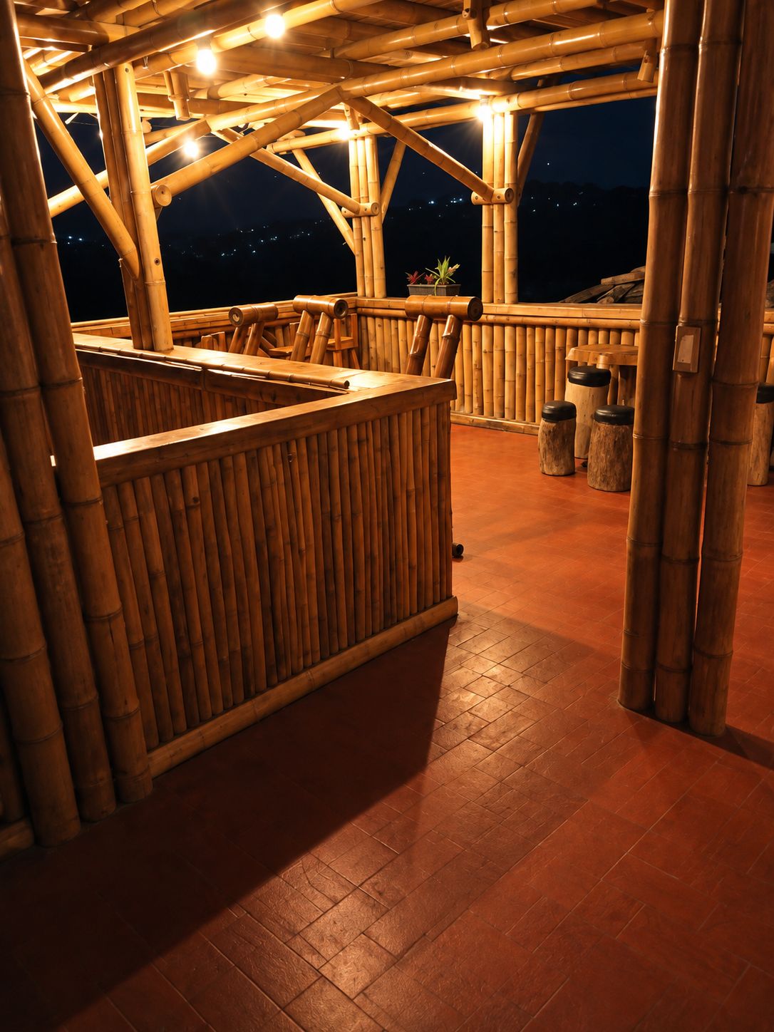 An outdoor bamboo structure with a seating area and a wooden counter.