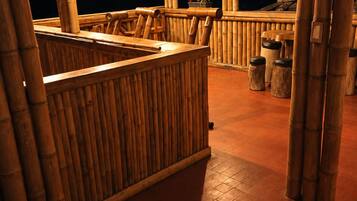 An outdoor bamboo structure with a seating area and a wooden counter.