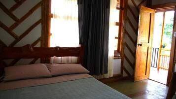Een slaapkamer met een houten bed, een raam met gordijnen en een deur naar een buitenruimte.