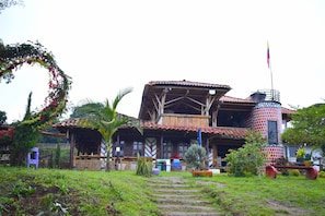 A traditional wooden house with a tiled roof, a balcony, and a flagpole. - Sanagua Cascadas del Lavapatas (San Agustín)