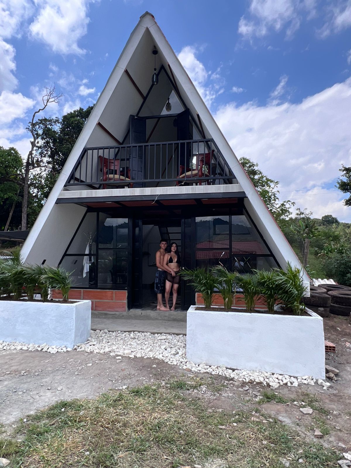 Un bâtiment moderne à deux étages, doté d’un toit triangulaire, d’un balcon et d’une entrée en verre.
