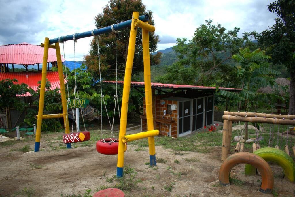 Un patio de recreo al aire libre con columpios y neumáticos colgantes.