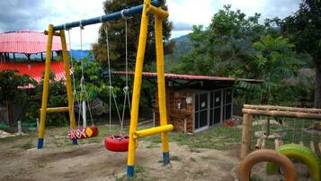 Un patio de recreo al aire libre con columpios y neumáticos colgantes.