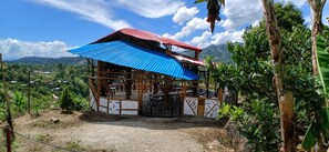 A two-story structure with a blue and red roof, surrounded by greenery and hills in the background. - Sanagua Cascadas del Lavapatas (San Agustín)